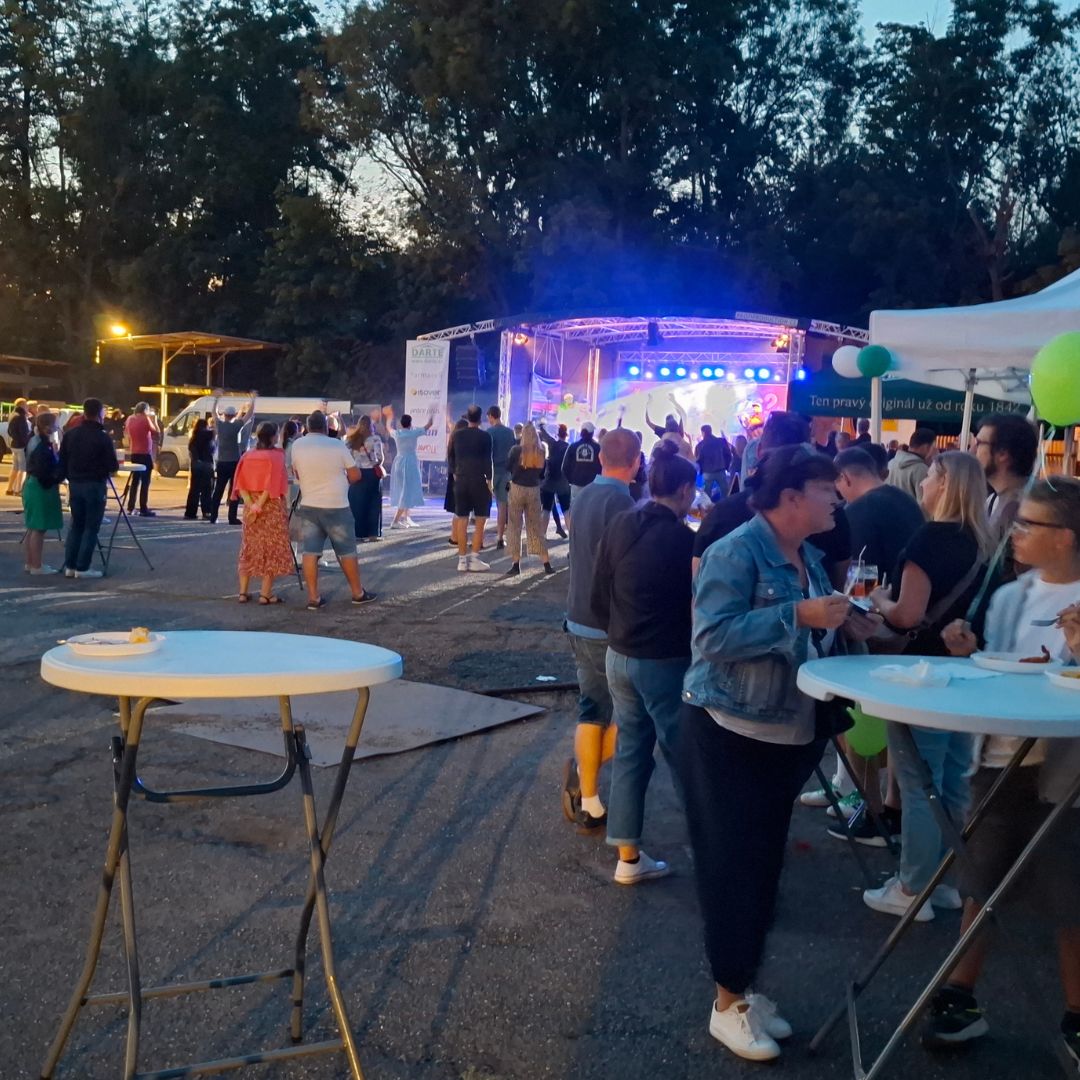 Pohled na osvětlené pódium a areál firemní akce za setmění, kdy tvořivý workshop končí